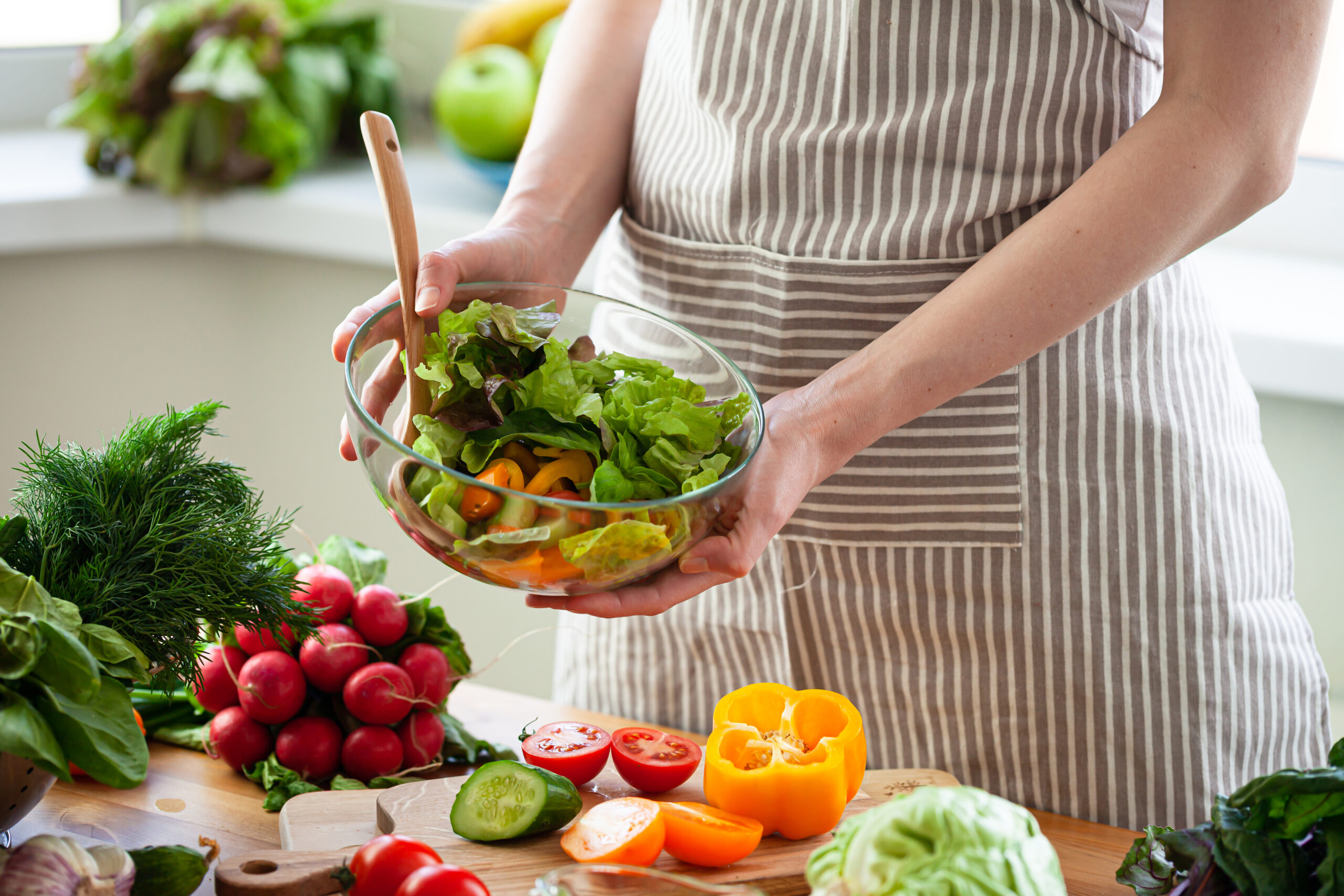 Beautiful young woman preparing delicious fresh vitamin salad. Concept of clean eating, healthy food, low calories meal, dieting, self caring lifestyle. Colorful vegetables, glass bowl. Close up